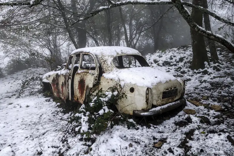 Old rusted car sitting in the snow